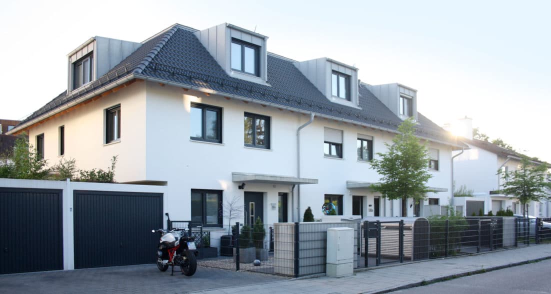 Mozartstraße 58 – Reihenhausanlage mit weißer Fassade, Dachgauben und Ziegeldach, Straßenansicht mit Vorgärten und Garagen
